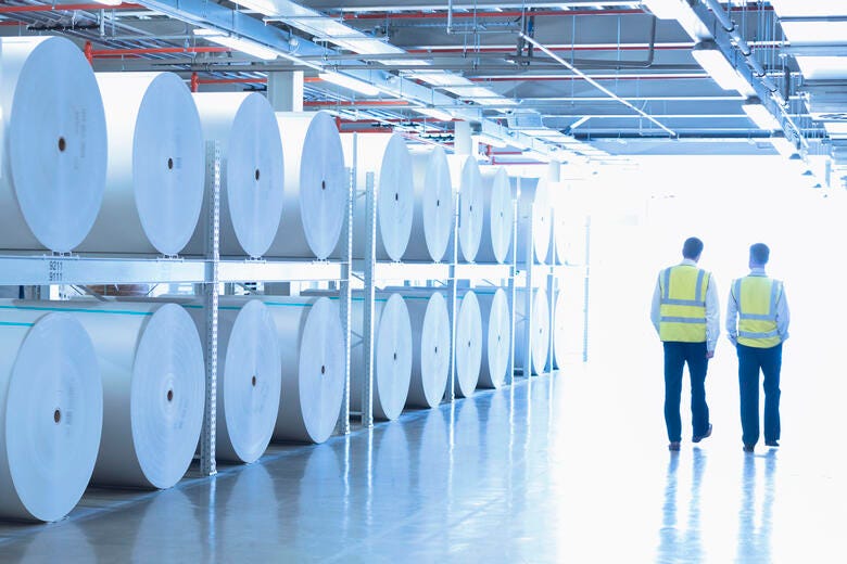 men in yellow vests standing in a room with white circular objects